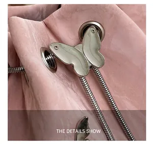 Detail van roze leren tas met zilveren vlinderschuiver en trekkoord met slangenketting
