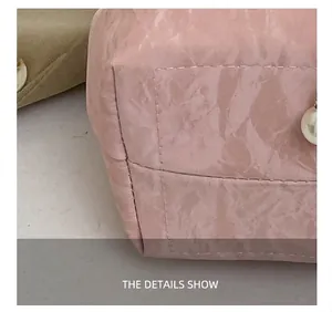 Detailopname van de roze emmertas met precisiestiksels en witte parelversiering