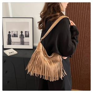 Close-up of tan suede tote bag featuring long decorative fringes and wide shoulder strap