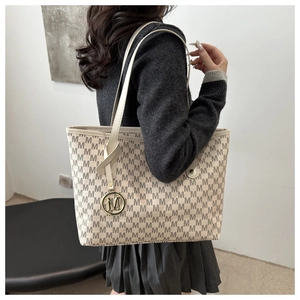 Macro shot of cream tote bag with monogram print and golden M metal pendant detail