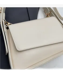 Detail van crème crossbodytas met nauwkeurige stiksels en lichtgouden metalen onderdelen