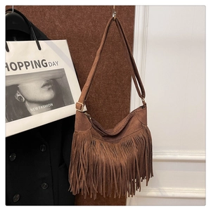 Close-up of brown suede fringe shoulder bag with bohemian tassels and metal buckle