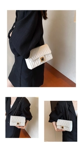 Details einer weißen Stepptasche mit goldenem Kleeblatt-Drehverschluss und Kettenriemen
