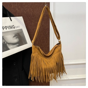 Close-up of a brown suede crossbody bag featuring long tassels and gold zipper closure