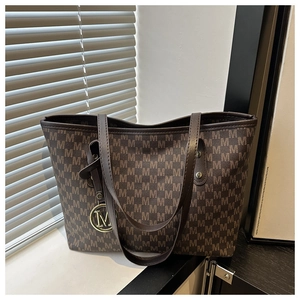 Close-up of brown tote bag featuring all-over M pattern and golden metal M charm
