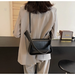 Detail van minimalistische zwarte lederen crossbodytas met gouden metalen accenten