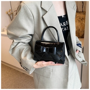 Detail einer glänzenden schwarzen Lackledertasche mit einer großen dekorativen Schleife