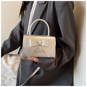 Detailansicht der silbernen Schleifen-Handtasche mit Metallic-Textur und Tragegriff