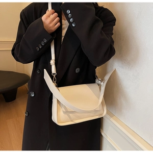 Detail of off-white faux leather crossbody bag with adjustable strap on a model