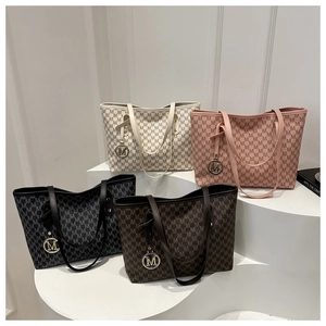 Close-up of four luxury tote bags with M letter print and round metal logo pendants