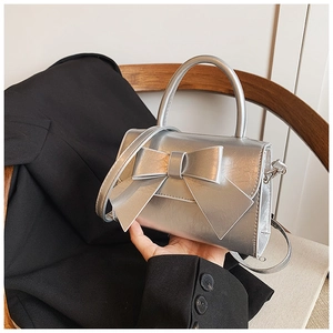 Detail einer silbernen Handtasche mit Schleife aus Metallic-Leder und quadratischer Klappe