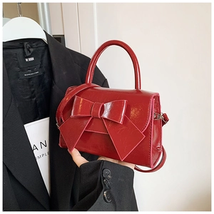 Kleine rote Lackleder-Handtasche mit großer Schleife in einem modernen Lifestyle-Setting