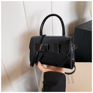 Detail der glänzenden schwarzen Handtasche mit Schleife und elegantem Rundgriff-Design