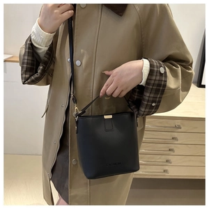 Détail d'un sac seau noir en cuir avec poignée supérieure et finitions dorées