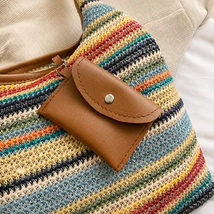 Close-up of the woven straw bucket bag featuring a brown leather pouch with silver hardware