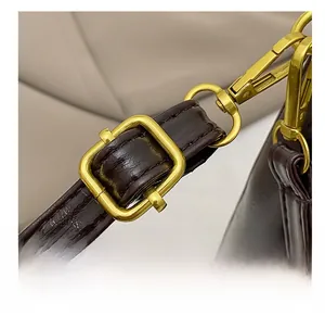 Detail showing the adjustable embossed leather shoulder strap with gold metal hardware buckle