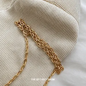 Detailed macro view of high-quality gold metal chain strap on a woven fabric surface