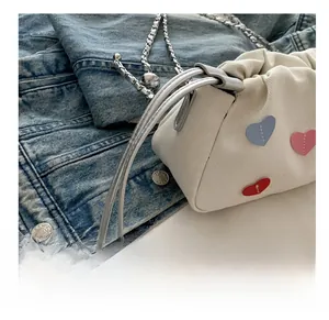 Detailed view of white canvas heart bag with silver chunky chain and beaded drawstring cord