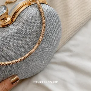 Detail of silver glitter evening clutch featuring a gold snake chain handle and jewel clasp
