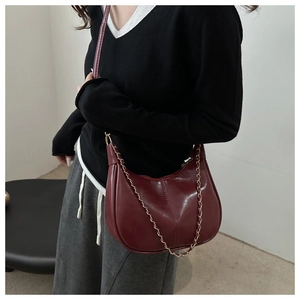 Détail du sac hobo bordeaux avec fini brillant, chaîne en métal et coutures verticales