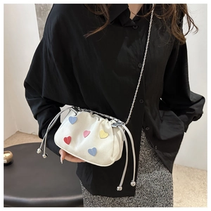 Detail view of the mini white drawstring chain bag with colorful heart-shaped patches