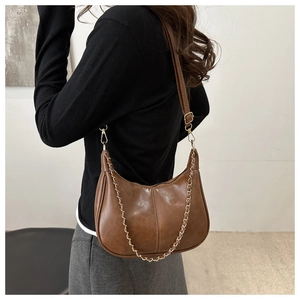Détail d'un sac hobo vintage marron avec bandoulière réglable et chaîne dorée