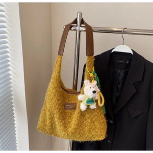 Detail of yellow plush tote bag with brown leather straps and cute dog doll accessory