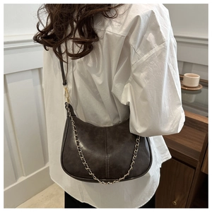 Détail macro d'un sac hobo marron foncé en cuir PU mat avec bandoulière chaîne dorée élégante