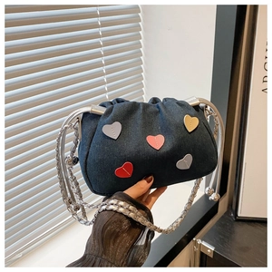 Detail of blue denim bucket bag with colorful heart patches and silver chain strap