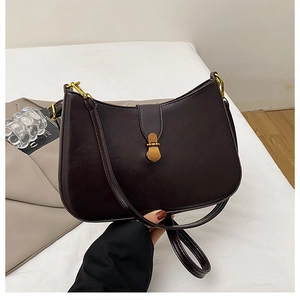 Detail of vintage chocolate brown crescent bag with retro gold metal clasp hardware