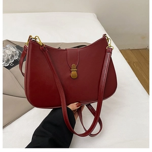 Detailed shot of dark red vintage underarm bag with gold metal clasp and pebble texture