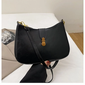 Detail of vintage black crescent underarm bag featuring a retro brass clasp closure