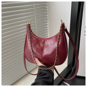 Détail du sac demi-lune en cuir bordeaux avec chaîne dorée et bandoulière en cuir