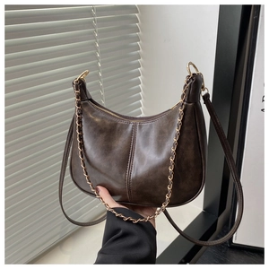 Détail de la texture en cuir marron lisse et de l'élégante bandoulière en chaîne dorée du sac