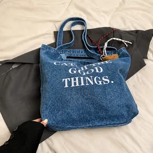Close-up of blue denim tote bag with Catch The Good Things print and plush charm accessory