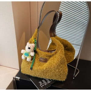 Detail of yellow wool tote bag with brown leather handles and a cute bear keychain