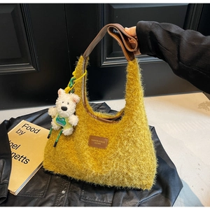 Detail of yellow fuzzy hobo bag with a plush bear charm and leather logo patch