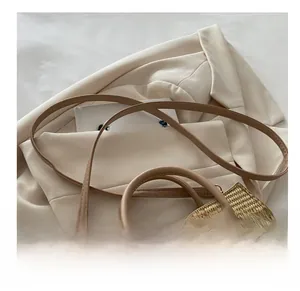 Detail of straw woven handbag with top handle and shoulder strap on beige fabric
