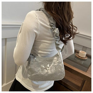 Silver metallic crossbody bag with textured pleats and butterfly charm close-up detail