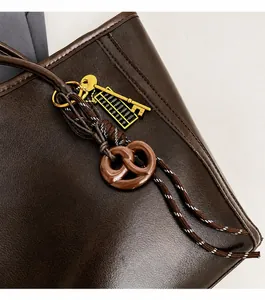 Detail of dark brown tote bag featuring vintage pretzel and golden abacus charms