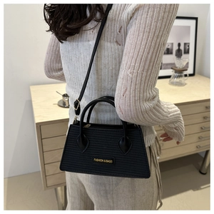 Close-up of black woven shoulder bag with gold 'FASHION & BAGS' text and adjustable strap