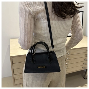 Detail of black woven shoulder bag with gold Fashion & Bags logo on a leather patch