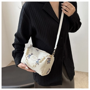 Detailed view of white puffy texture bag with cartoon bears and pearl gold chain