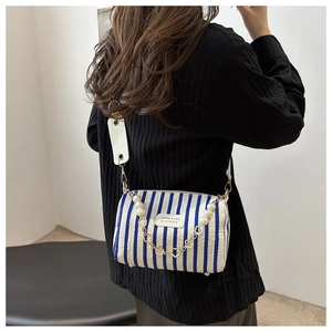 Detail of blue and white striped fabric bag with pearl chain and heart charm