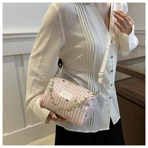 Detail of pink striped barrel bag with pearl chain and leather label on white blouse
