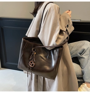 Close-up of a large coffee brown tote bag featuring glossy texture and circular charm