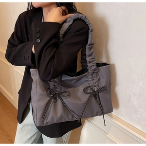 Gros plan du sac cabas plissé gris avec nœuds noirs et surpiqûres blanches contrastées