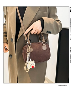 Detail of vintage brown suede crossbody bag with cute plush biscuit charm and strap