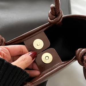Détail du fermoir magnétique en métal et de la poignée nouée sur un sac seau marron rétro