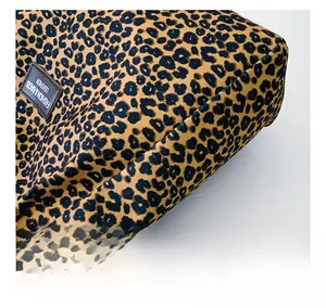 Detailed view of the leopard print fabric stitching and faux leather logo on the tote bag